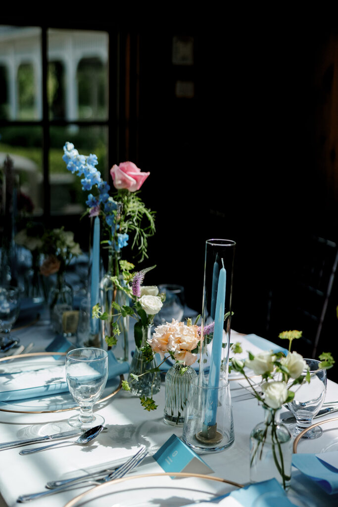 Reception table décor with blue accents and taper candles, ideal inspiration for thoughtful wedding detail photos.