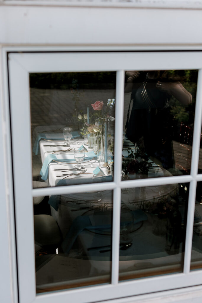 Reception table seen through a window, a unique perspective for wedding detail photography that highlights atmosphere and design.