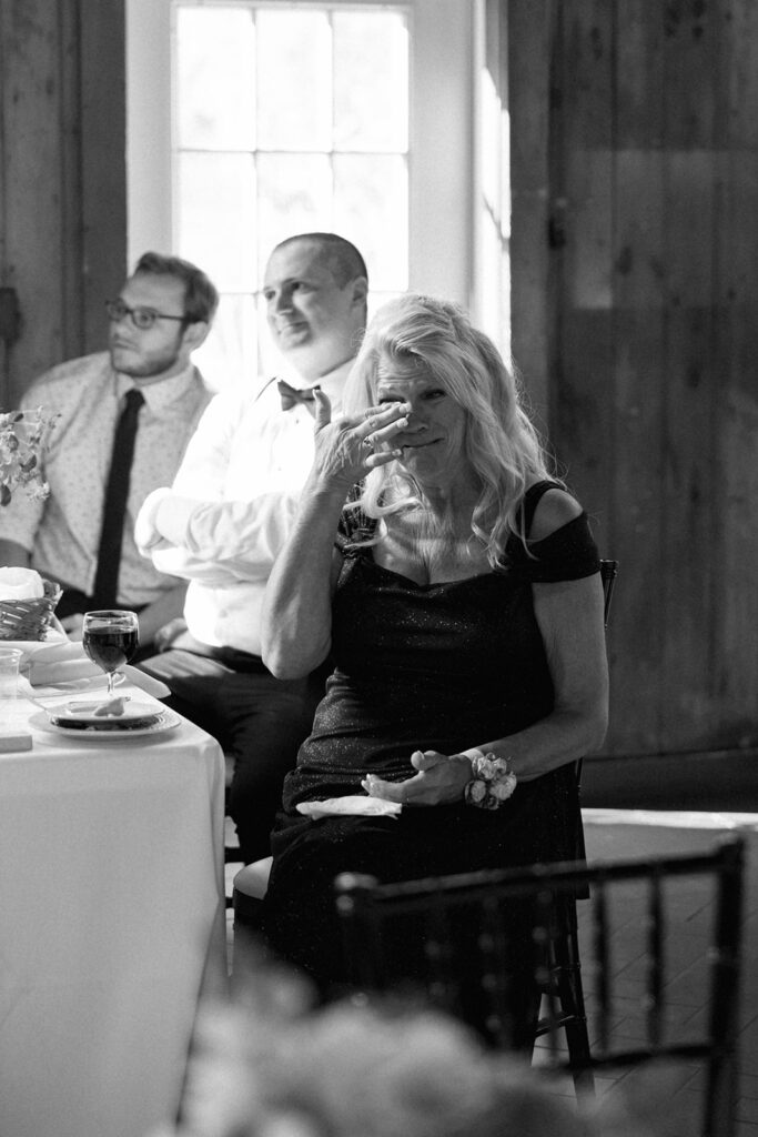 Parents watching ceremony speeches inside venue, full of emotion and warmth.