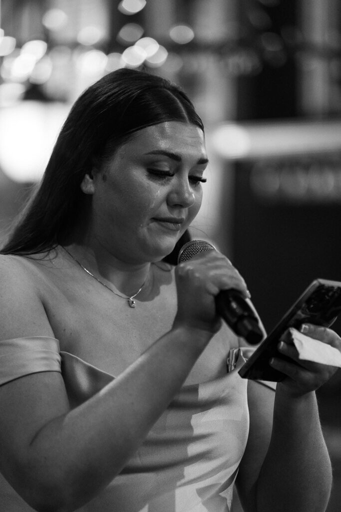 Guest wiping away tears during wedding toasts, a deeply emotional documentary-style photo.