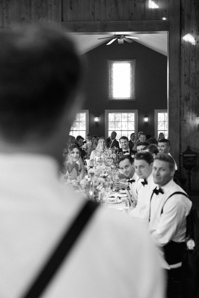 Reception crowd viewed from behind a guest’s shoulder, a journalistic angle for documentary-style wedding photography.