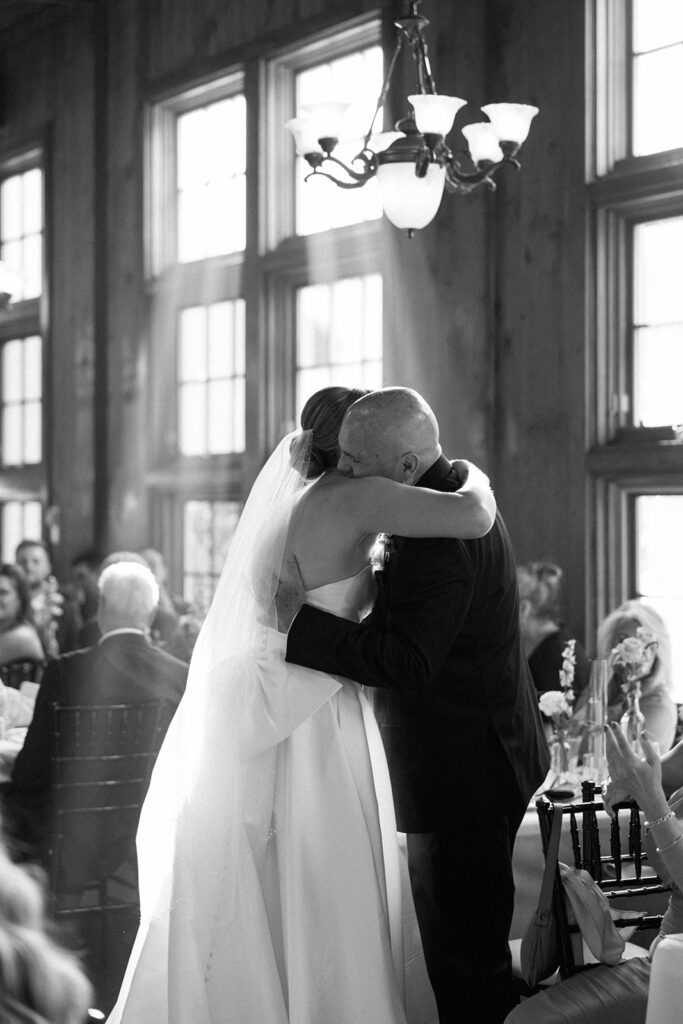 Bride hugging her father inside ceremony space, a meaningful father-daughter moment captured candidly.