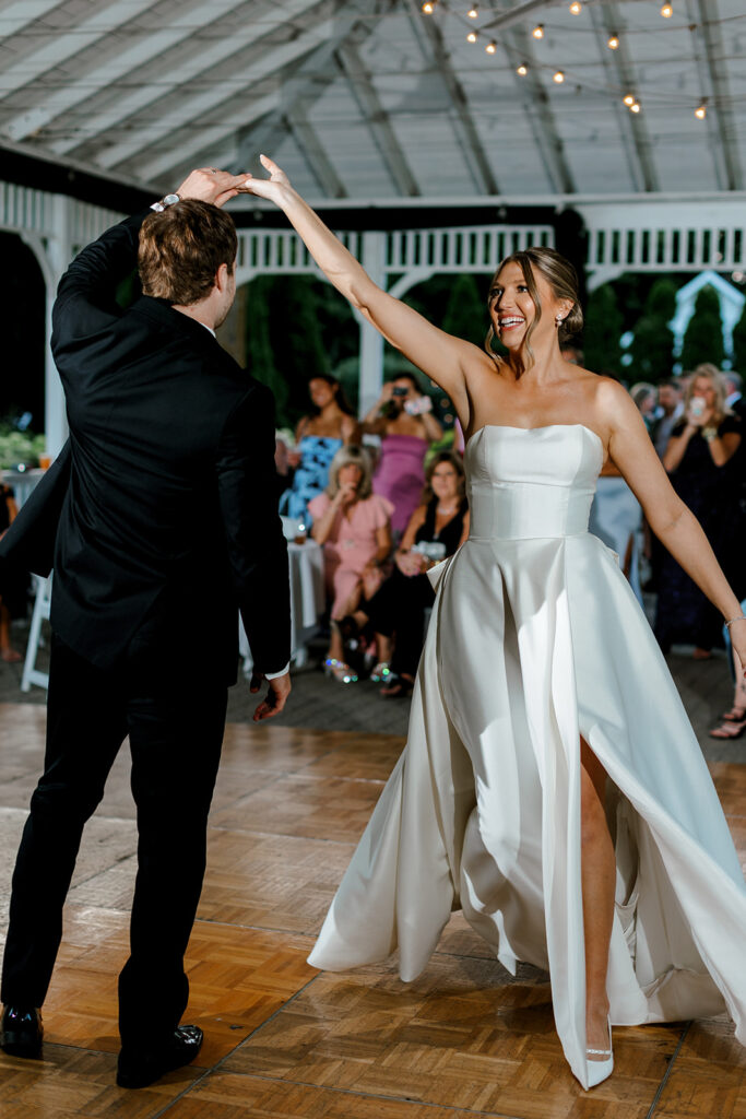 Bride twirling on the dance floor in her gown, a fun and lively moment to include in your wedding shot list.