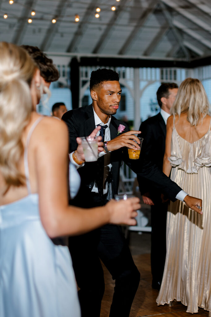 Guest dancing with champagne in hand under twinkle lights, a classic candid for Michigan wedding receptions.