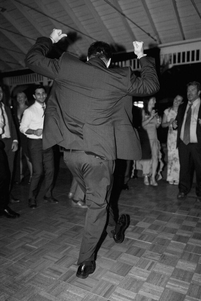 Black and white photo of guest mid-dance, capturing documentary-style energy at the wedding party.